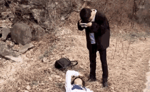 a man is taking a picture of a woman laying on the ground ..