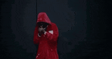 the man is wearing a red hoodie and smoking a cigarette .