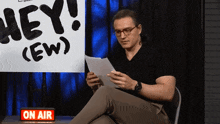 a man sitting in front of a sign that says hey
