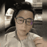 a man wearing glasses and ear buds is sitting in the back seat of a car