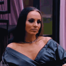 a woman wearing a black off the shoulder top is sitting in front of a window ..