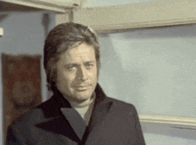 a man in a black coat is standing in front of a door