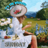 a woman in a hat is sitting at a table drinking a glass of wine and reading a book .