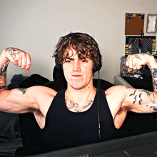 a man wearing headphones flexes his muscles in front of a poster that says viri