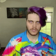a man with purple hair is wearing a colorful shirt with unicorns on it