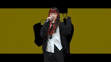 a girl with red hair singing into a microphone with a fist in the background