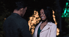a man and a woman are looking at each other in front of christmas lights