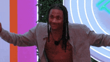a shirtless man with dreadlocks is standing in front of a wall