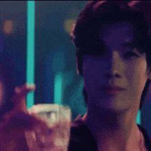 a close up of a person holding a glass in a dark room