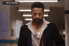 a man in a suit is standing in a hallway with 7wickreddy written on the bottom right corner