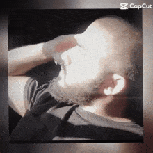a man with a beard is laying down with his eyes closed and a capcut logo in the corner