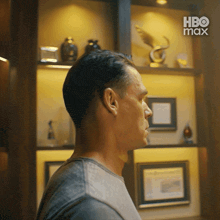a man standing in front of a shelf with a hbo max logo on it