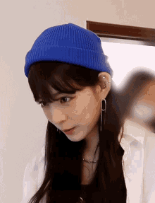 a young woman wearing a blue beanie and earrings