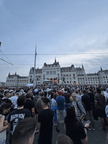 a crowd of people are gathered in front of a large building and one man is wearing a death row shirt