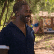 a man with a beard and mustache is smiling while standing in a park .
