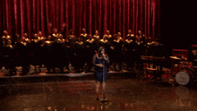 a woman sings in front of a choir and a drum that says jazz
