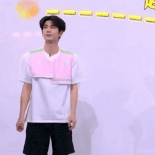 a man in a white shirt and black shorts is standing in front of a wall .