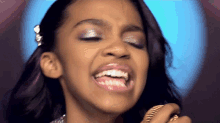 a young woman singing into a microphone with her eyes closed
