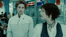 a man and a woman are standing next to each other in a hallway with flags in the background