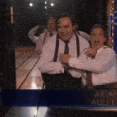 a group of men are hugging and laughing in front of a sign that says " aria auli "