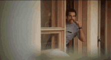 a man with a mustache is looking out of a window