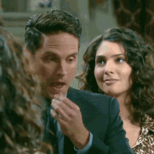 a man in a suit and tie is talking to a woman with curly hair