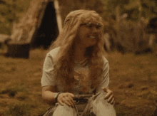 a woman with curly hair is laughing while sitting on the ground