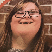 a girl with glasses and missing teeth smiles for the camera