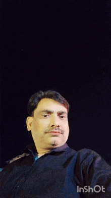 a man with a mustache stands in front of a group of people in a room