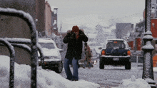a man in a red hat is walking down a snow covered street