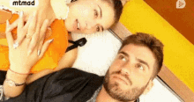 a man and a woman are laying next to each other on a bed and looking at the camera .
