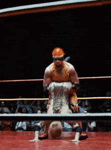 a wrestler wearing a hard hat is wrestling another wrestler