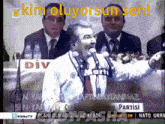 a man speaking into a microphone with the words kim oluyorsun sen on the bottom
