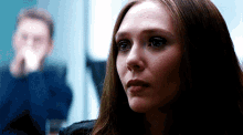 a close up of a woman 's face with a blurry man in the background