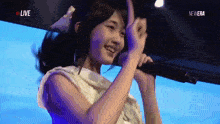 a woman is singing into a microphone with the words live in the corner