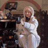 a woman in a hooded jacket is kneeling down in front of a camera .