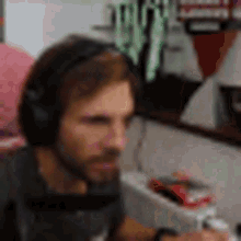 a man with a beard wearing headphones is sitting in front of a computer .