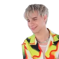 a young man wearing a colorful shirt and necklace is smiling with his eyes closed