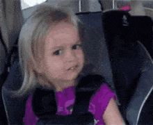 a little girl is sitting in a car seat with her mouth open