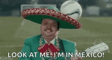 a man in a mariachi outfit is holding a guitar and a soccer ball in his hat .
