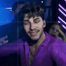 a man in a purple shirt with a tattoo on his chest is smiling