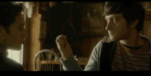 a man and a woman are sitting at a table looking at each other in a room .