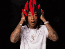 a man wearing a white shirt and a cam necklace holds his hands to his head