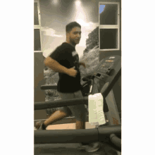 a man in a black shirt is running on a treadmill with a towel hanging from it