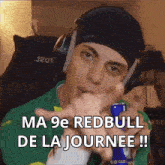 a man wearing headphones and holding a can of red bull