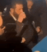 a man in a suit is talking into a microphone while standing in a crowd of people .