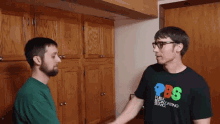 two men shaking hands one wearing a pbs shirt