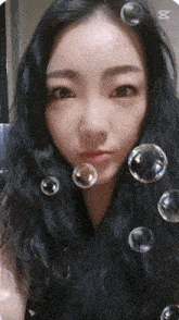 a woman surrounded by soap bubbles with the letter m on the bottom