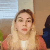 a woman with blonde hair and earrings is making a funny face