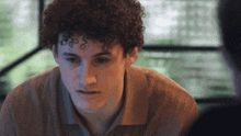 a young man with curly hair looks at something
